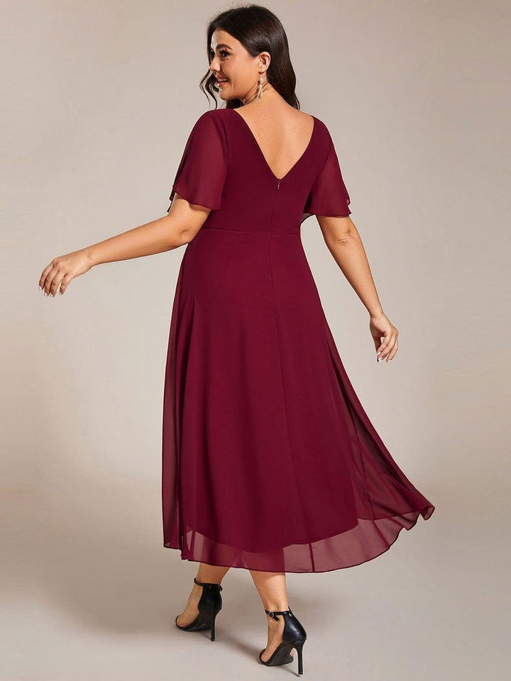 Back view of the burgundy dress on a plus-size model, showing the V-back, center zipper and layered chiffon hem. 50