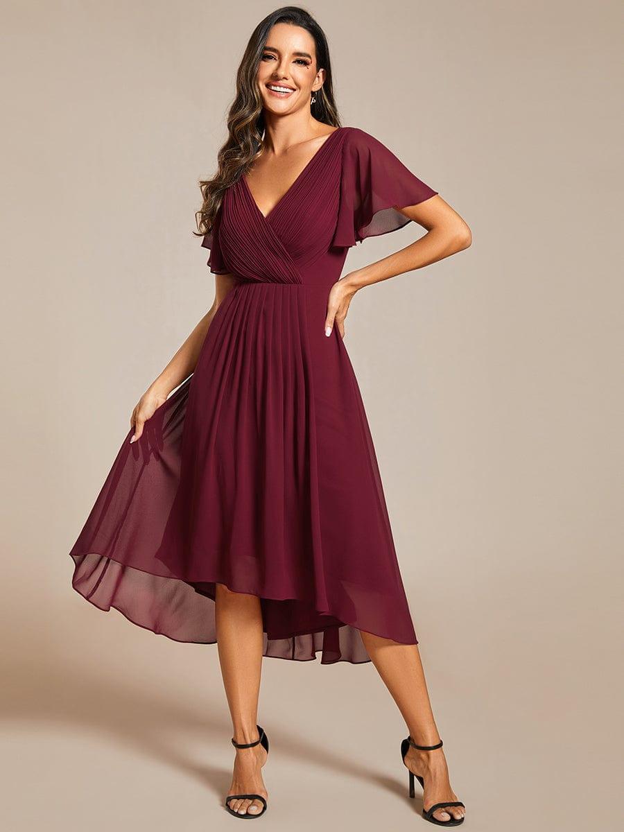 Model in the burgundy dress smiling with one hand on her hip, lifting the sheer chiffon skirt to show the high-low hem. 48