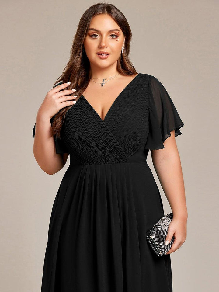 Close-up of a plus-size model in the black dress, showing the pleated V-neck bodice and sheer sleeves, holding a rhinestone clutch. 28