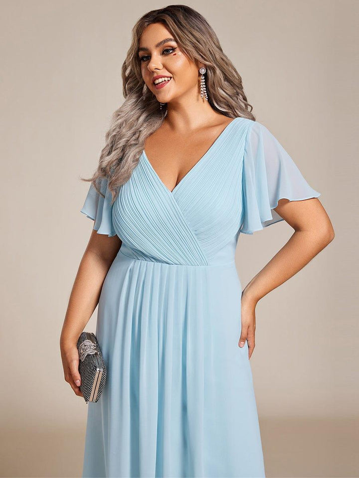 Close-up of the light blue dress's pleated bodice and sleeves on a laughing plus-size model with a studded clutch. 91