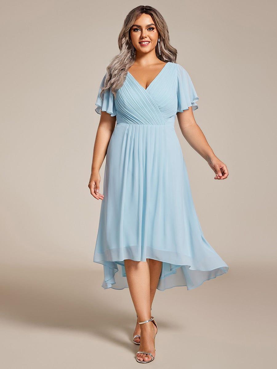 Plus-size model walking forward in the light blue chiffon dress with pleated wrap bodice and silver ankle-strap sandals. 89
