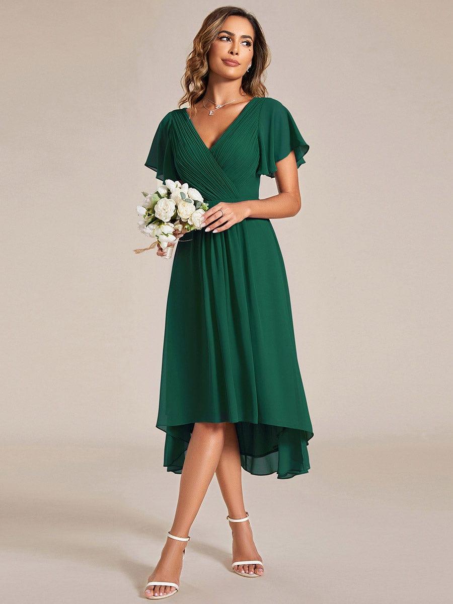 Model in the dark green dress holding a white flower bouquet, showing the front-short, back-long hemline. 13