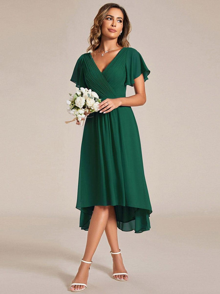 Model in the dark green dress holding a white flower bouquet, showing the front-short, back-long hemline. 13
