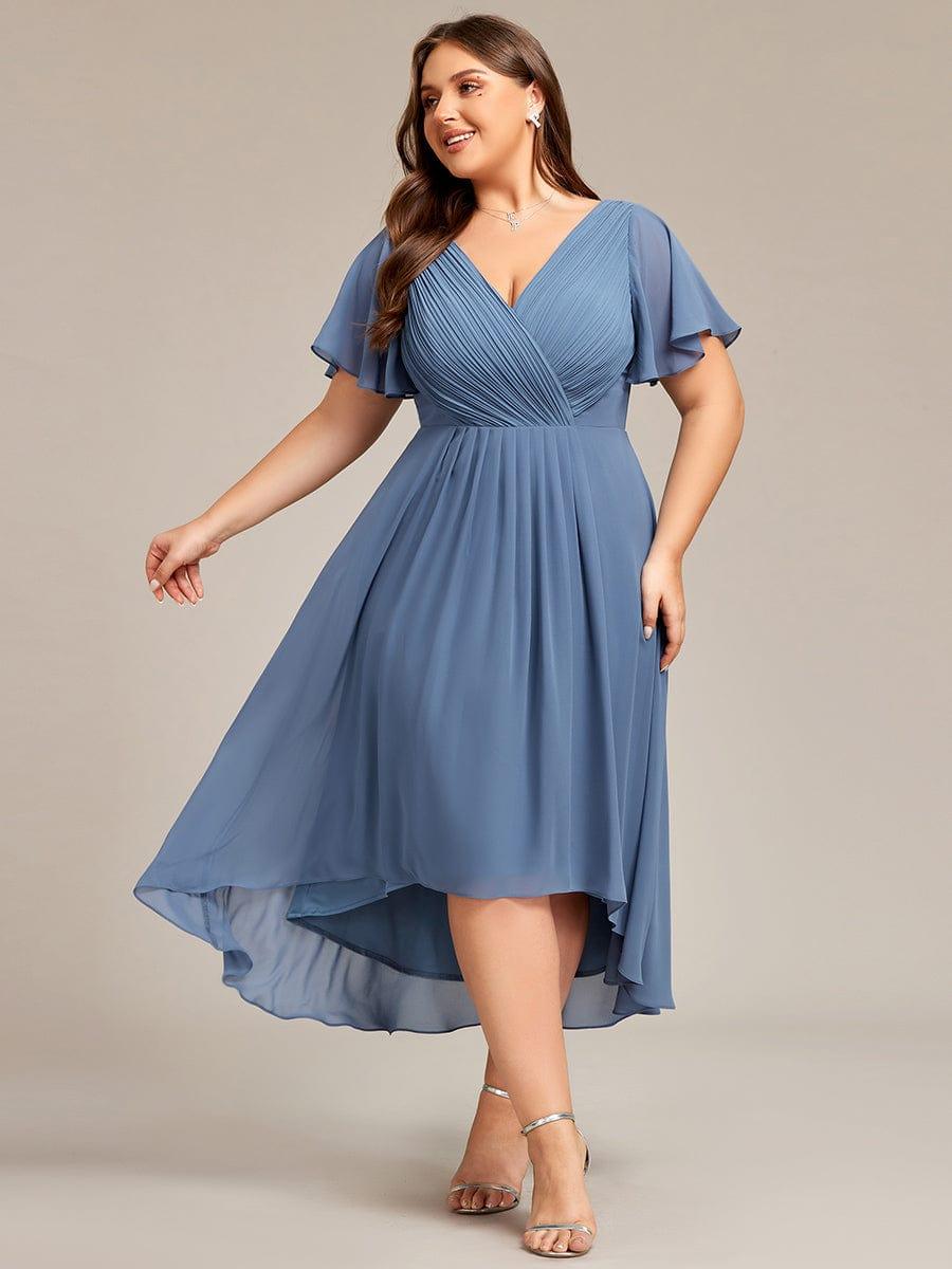 Plus-size model in dusty blue pleated chiffon dress with flutter sleeves, high-low hem and silver sandals, twirling the skirt. 41