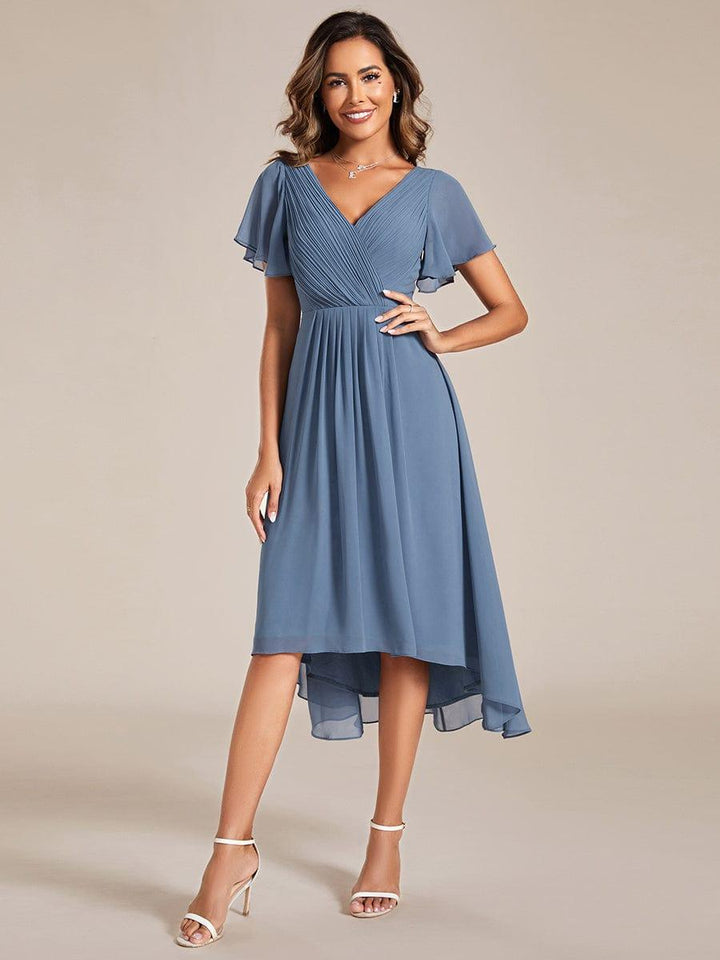 Dusty blue chiffon dress worn by a model with one hand on her hip, front view with white heeled sandals. 5