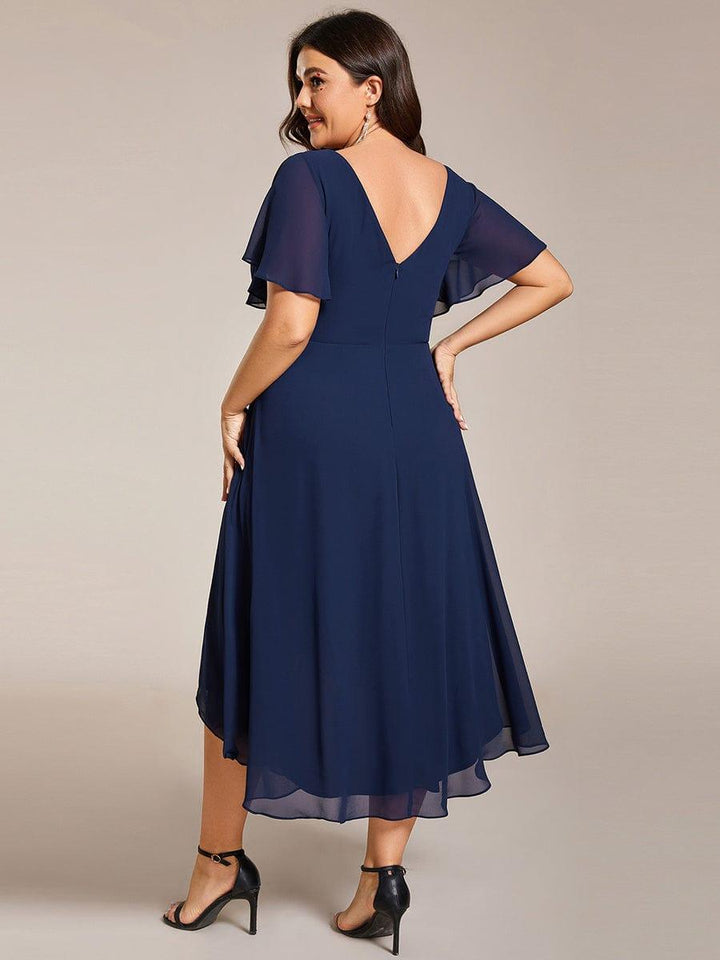 Back view of the navy dress on a plus-size model, showing the V-back, center zipper and layered high-low chiffon hem. 56