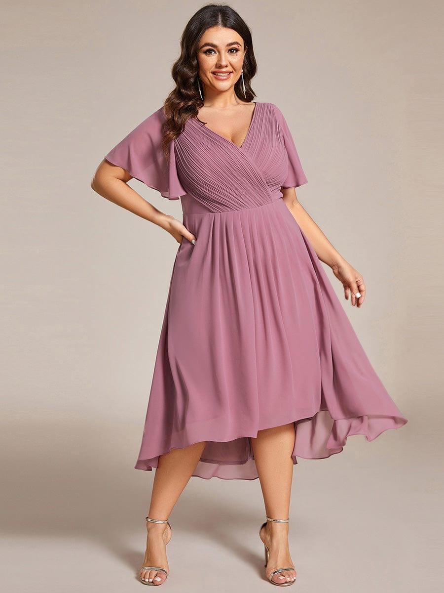 Plus-size model posing with one hand on her hip in the mauve pink chiffon dress with an uneven high-low hem. 66