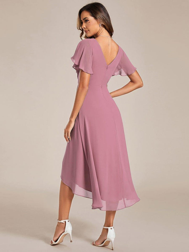 Back view of the mauve pink dress, showing the V-shaped back, zipper and asymmetric high-low chiffon hem with white heels. 59