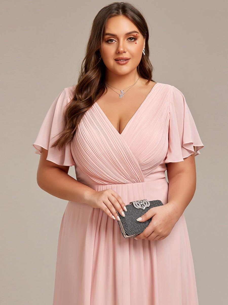 Close-up of a plus-size model in the pink dress, showing the pleated wrap bodice and flutter sleeves, holding a clutch. 33