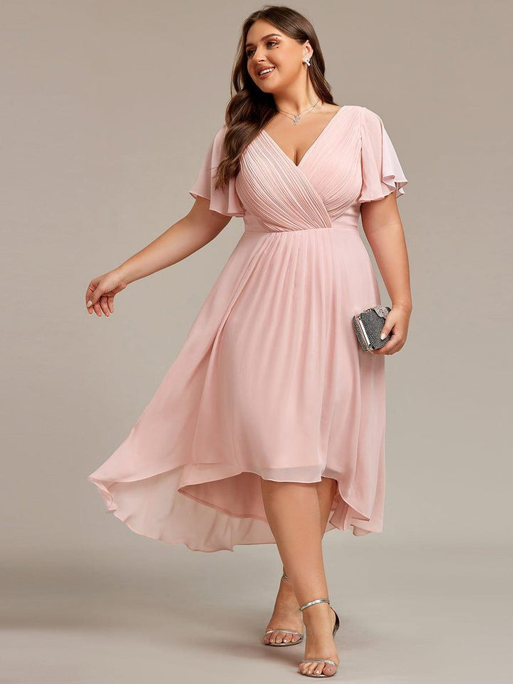 Plus-size model in the light pink version of the dress, walking with a clutch and silver sandals, hem flowing. 31
