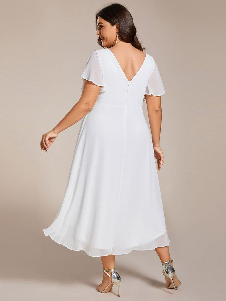 Back view of a plus-size model in the white chiffon dress, showing the V-back, center zipper and curved hem. 74