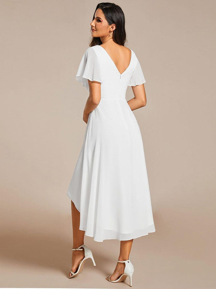 Back view of a model in the white chiffon dress, showing the deep V-back, zipper and longer hem at the back. 69