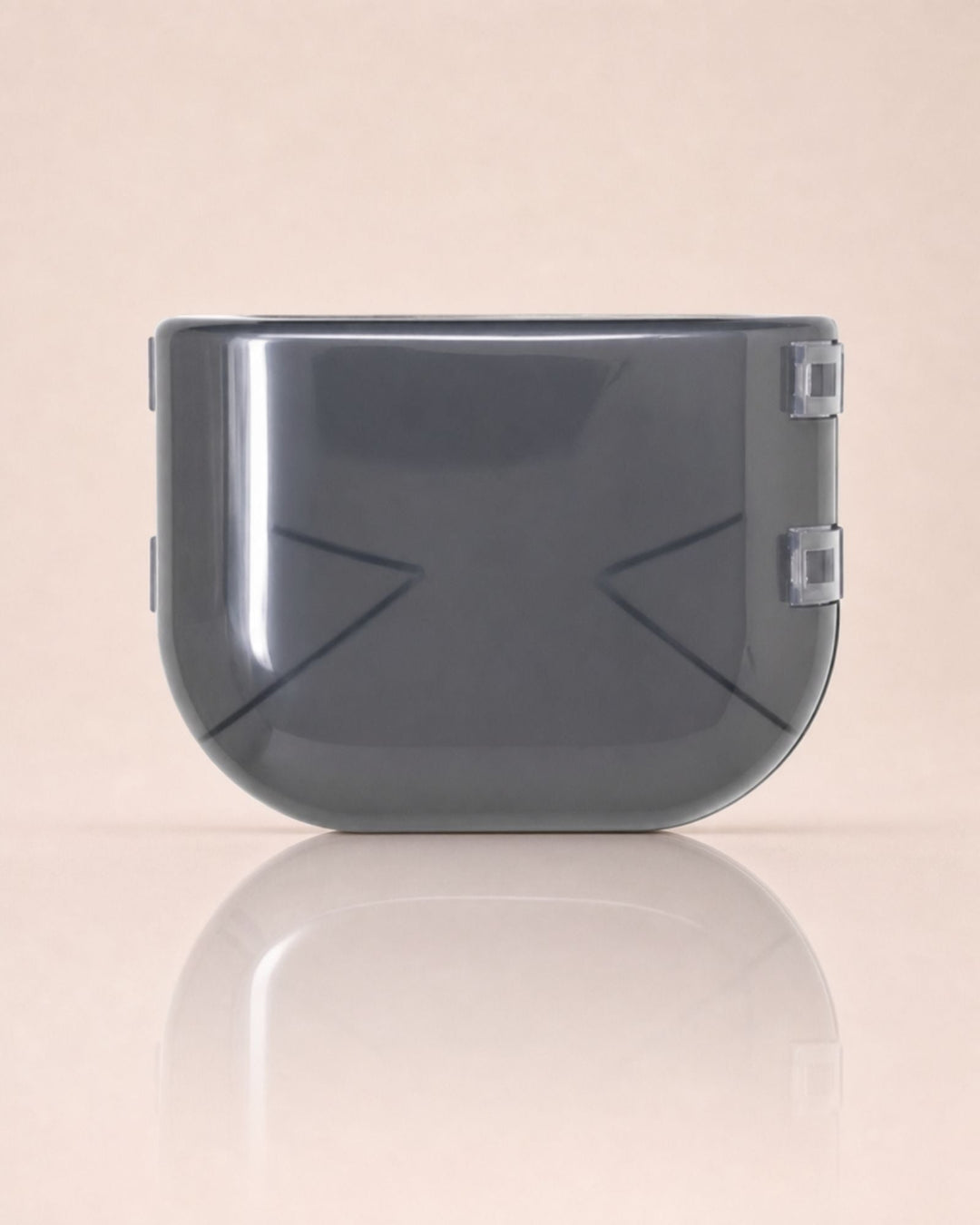 Smoky gray translucent protective case with clasps on the sides on a reflective pale pink surface.