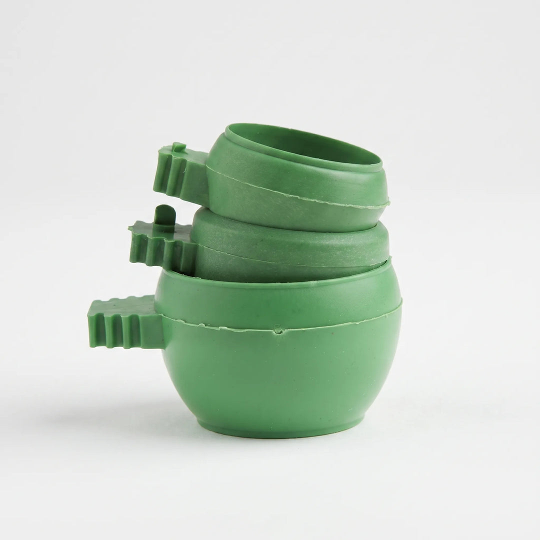 Three green plastic bowls with ridged clip handles stacked together on a plain white background, showing their rounded shape. 1
