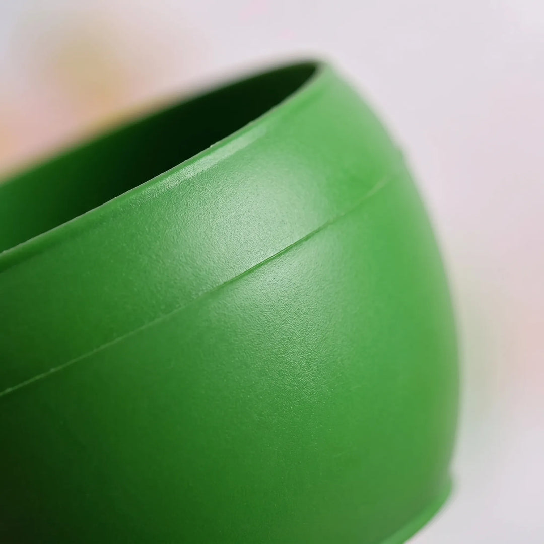 Close-up of the smooth green plastic bowl's curved side and rim, showing the seam line and fine surface texture. 3