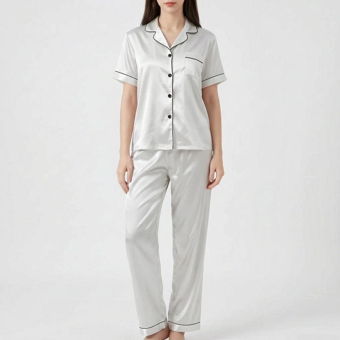 Woman in the white satin version of the pajama set with black piping and black buttons, shown from the front. 10
