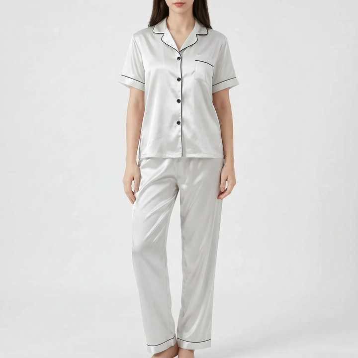 Woman in the white satin version of the pajama set with black piping and black buttons, shown from the front. 10