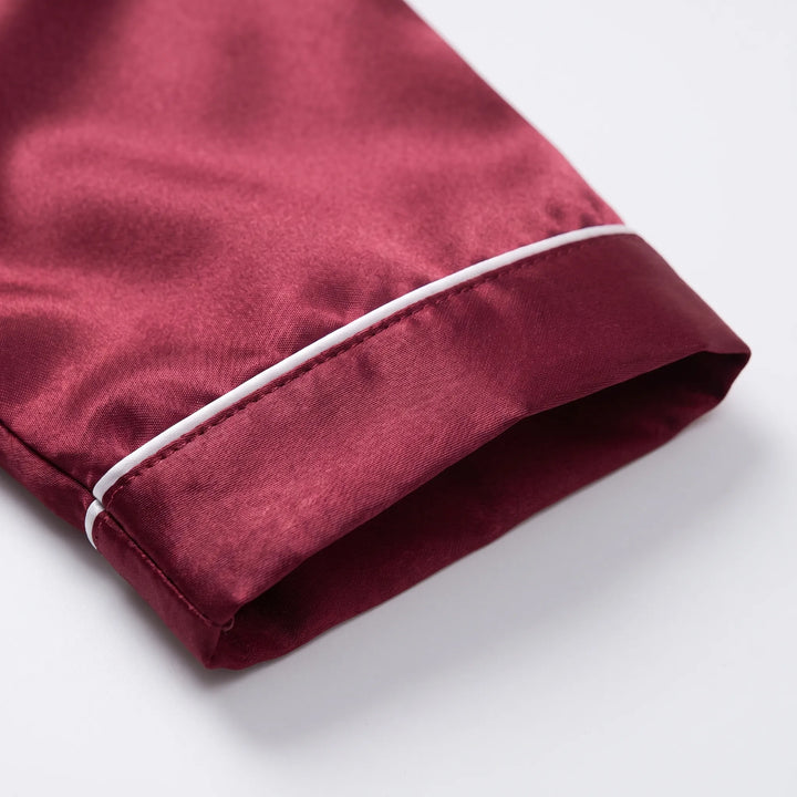 Close-up of a burgundy satin sleeve cuff with white piping and neat stitching on a white background. 5
