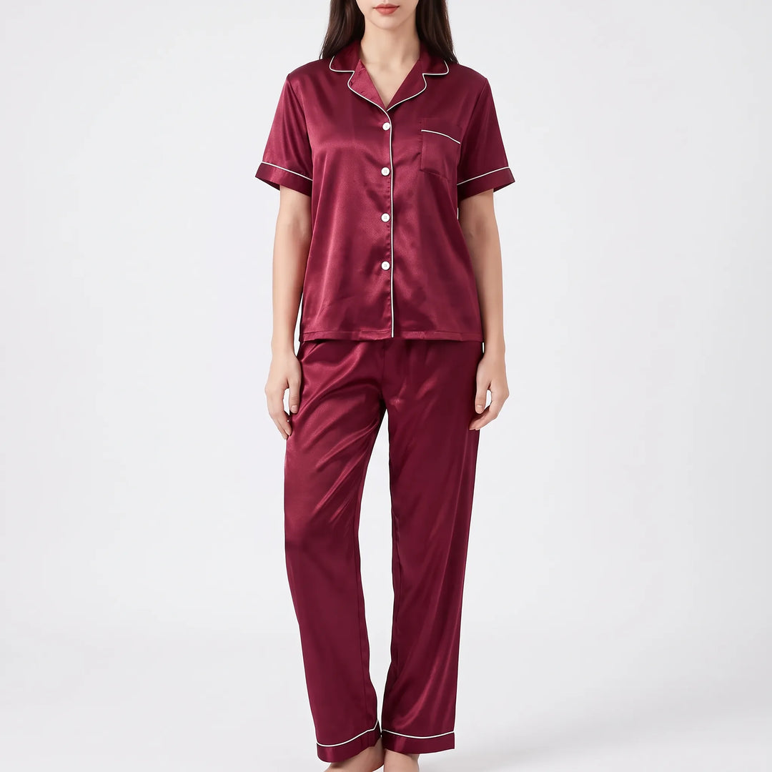 Studio front view of a woman wearing the burgundy satin pajamas with white buttons, piped collar and pocket, and long pants. 6