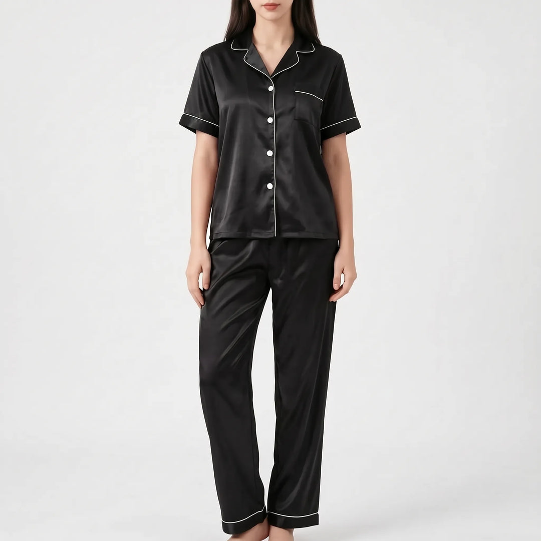 Woman in the black satin version of the pajama set with white piping and white buttons, shown from the front. 7