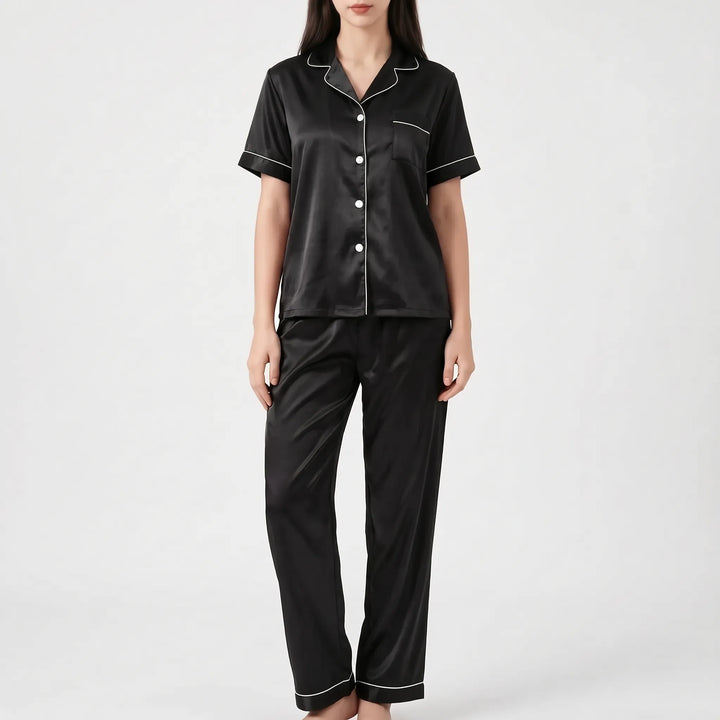 Woman in the black satin version of the pajama set with white piping and white buttons, shown from the front. 7