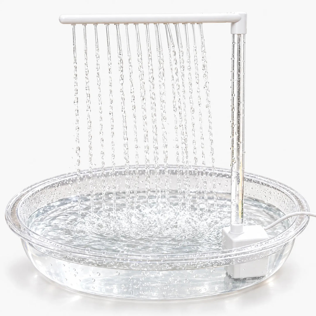 Clear shallow basin with a white pump and upright arm, many thin streams of water falling from the arm into the pool. 1