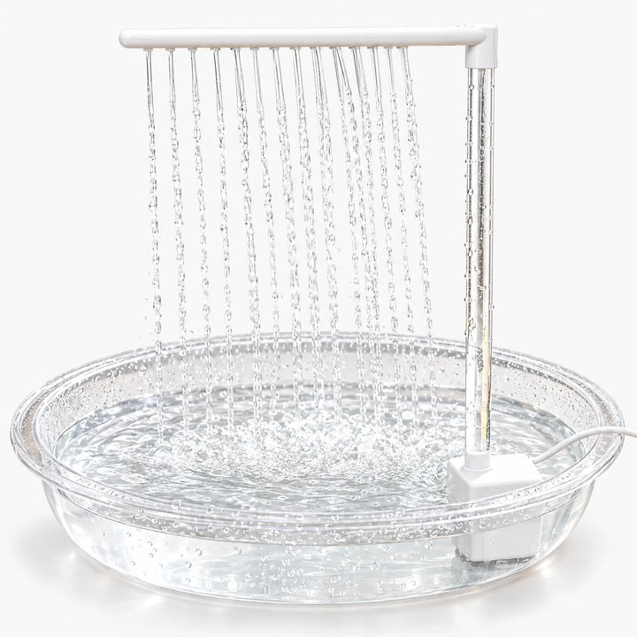 Clear shallow basin with a white pump and upright arm, many thin streams of water falling from the arm into the pool. 1