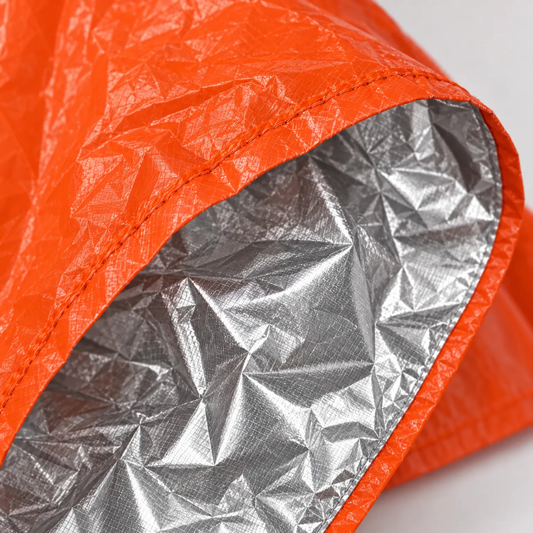Close-up of the orange poncho's stitched edge, with the crinkled silver reflective lining folded back to show the inside. 5