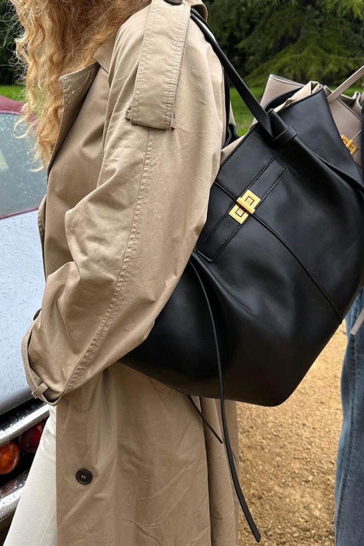 Black nylon tote detail shown from the side, with gold lock visible.