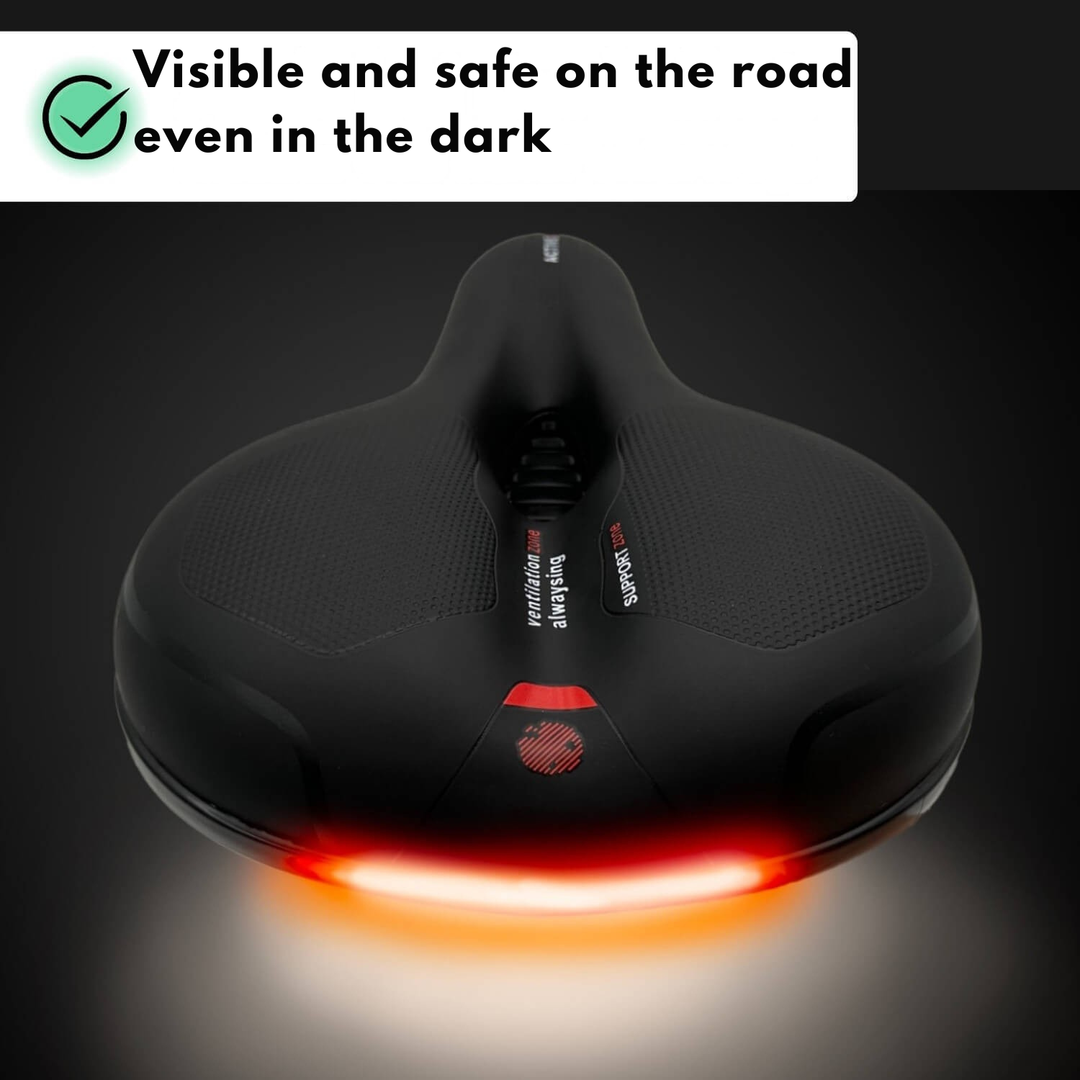 Rear of the black saddle in a dark setting with a glowing red reflective strip.