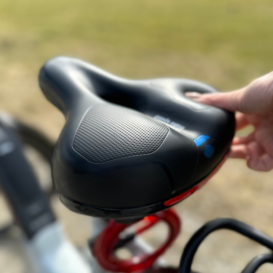 Another view of a black saddle with blue accents mounted on a bicycle outdoors.