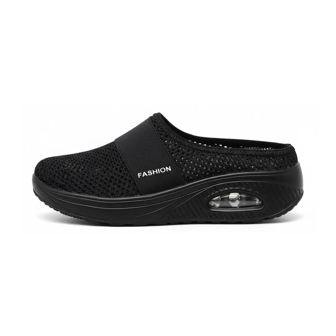 Side view of a single black mesh slip-on clog showing the elastic strap and the visible air-cushion window in the thick sole. 23