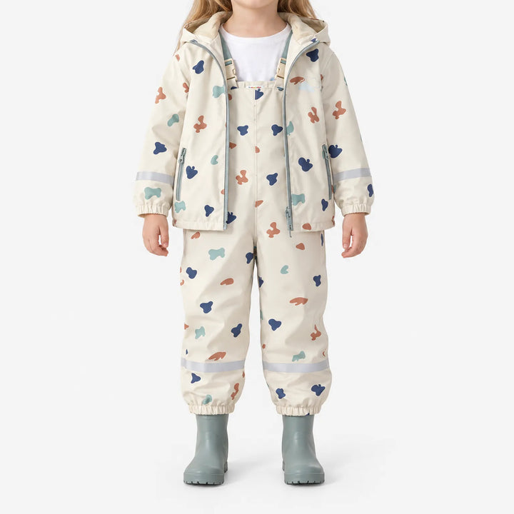 Child standing in the open jacket over the bib-style pants, showing the buckled straps and soft fleece lining, with sage rain boots. 2