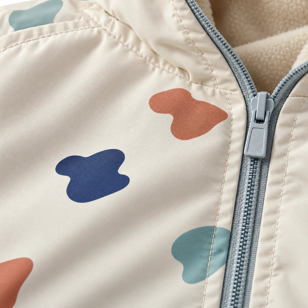 Close-up of the jacket collar showing the gray-blue zipper, soft cream fleece lining and the printed orange, navy and teal blob shapes. 6