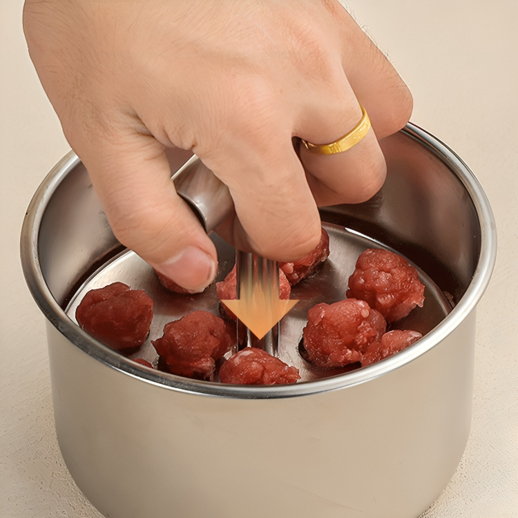 Detail of a hand pushing the handle down in the steel cup over raw meatballs with an orange arrow. 5
