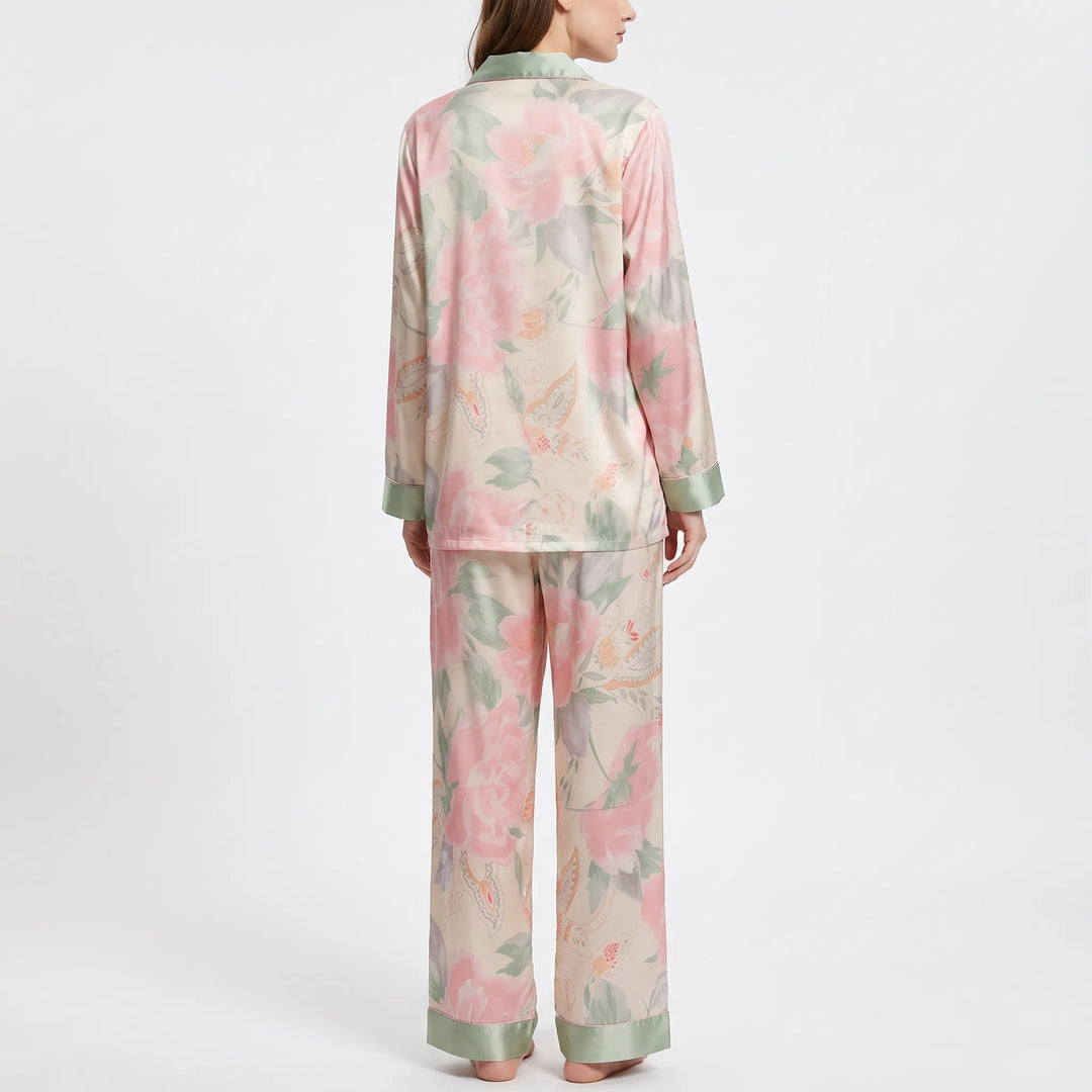 Back view of the model wearing the pink floral pajama set, showing the large flower print and green cuffs on full-length pants. 3