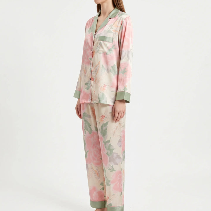 Three-quarter side view of the model in the pink floral pajamas, showing the chest pocket, buttons and green-trimmed pant hems. 4