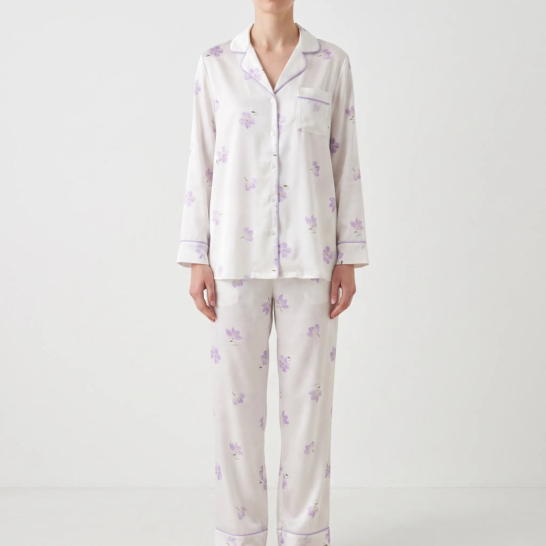 Model in a different pajama set: white satin with scattered lavender flowers and lavender piping, shown from the front. 8