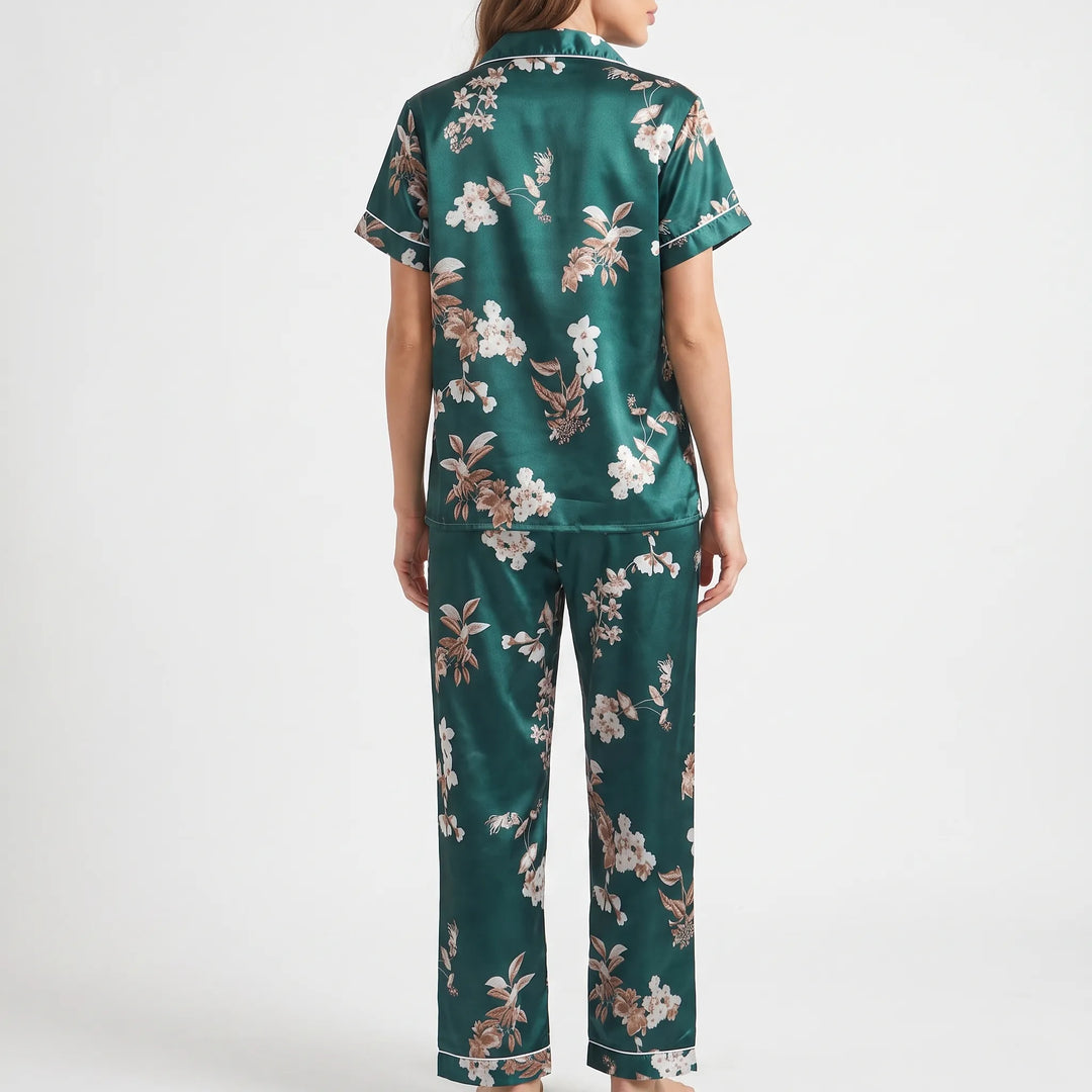 Back view of the model wearing the green satin pajama set, showing the scattered floral print across the top and long pants. 3