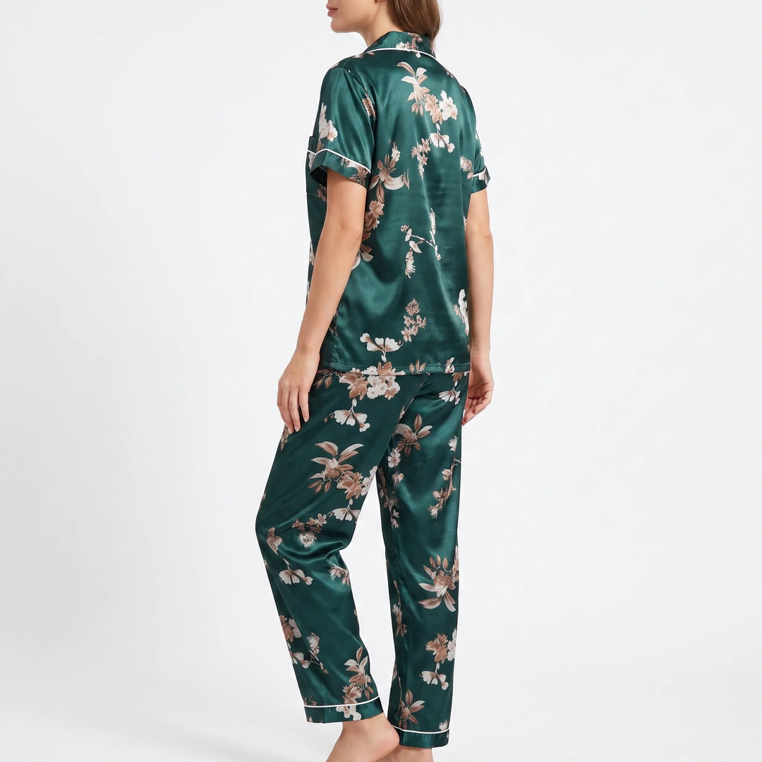 Three-quarter back view of the model in the floral satin pajamas, showing the short sleeve with white piping and the pants. 4