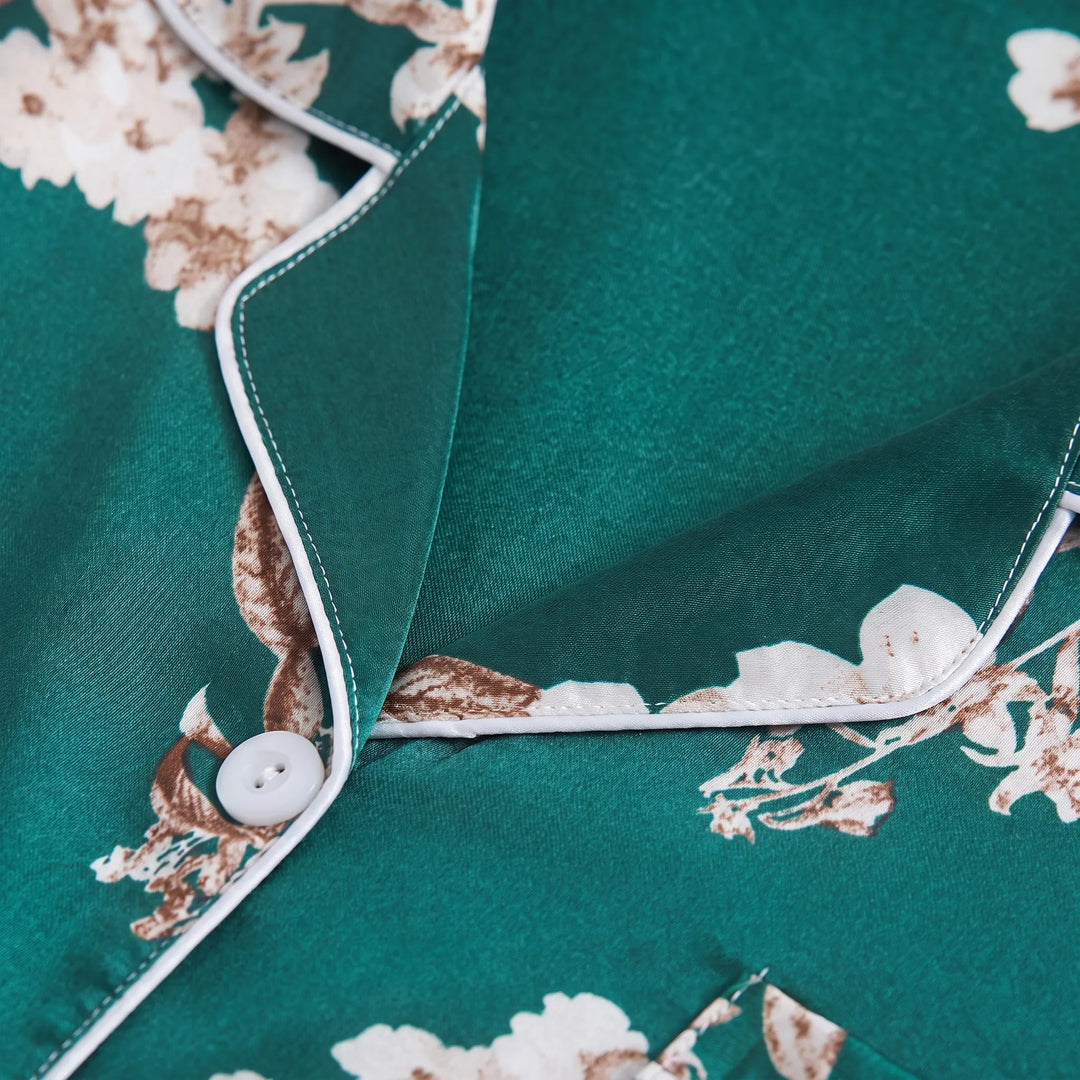 Close-up of the notched collar with white piping, a white button and the glossy satin fabric with cream and brown flowers. 5