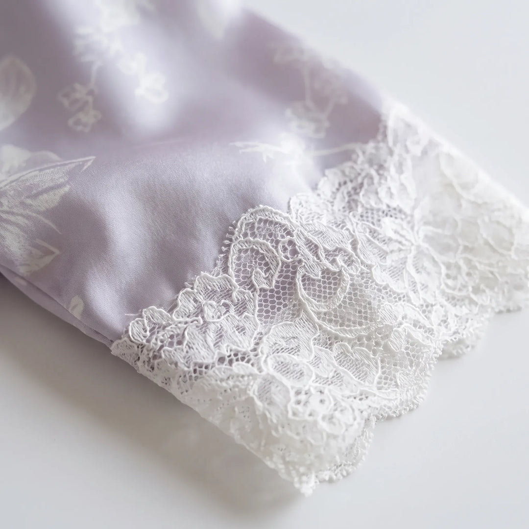 Close-up of a lavender satin sleeve with a scalloped white lace cuff, resting on a white surface. 5