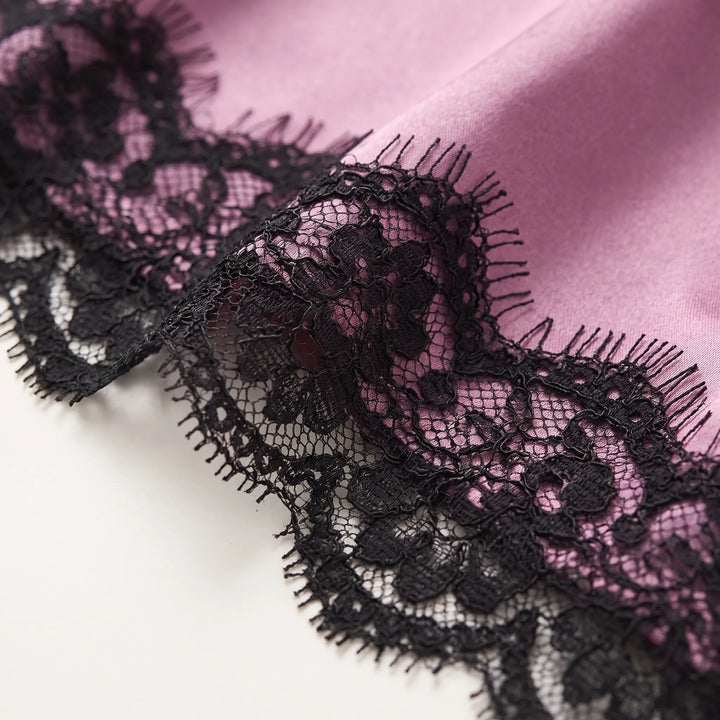 Close-up of black eyelash lace edging stitched onto smooth mauve satin fabric. 4