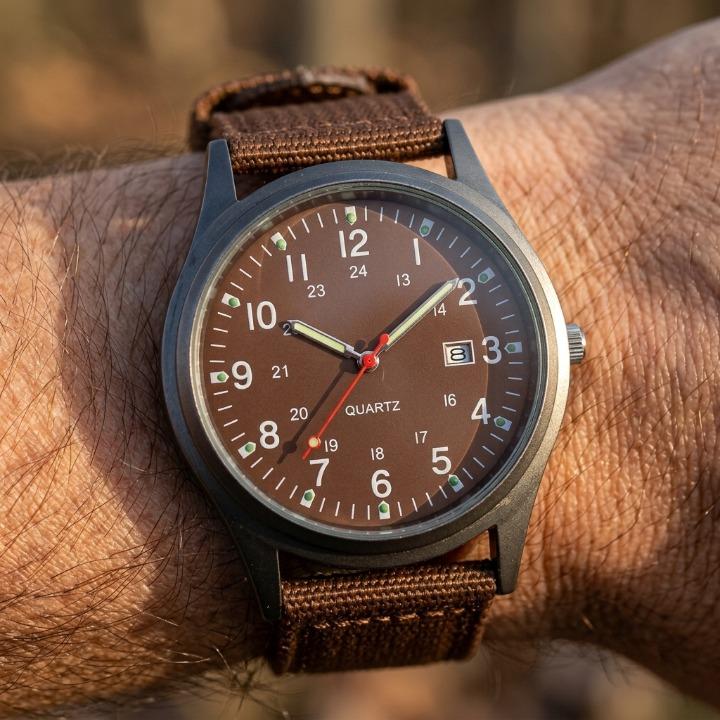 Brown military watch with nylon strap, detail view showing luminous hands, markers and the woven strap.