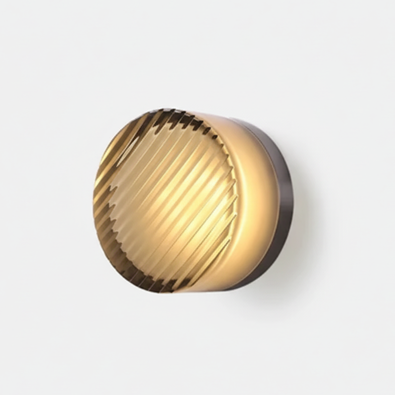 Wall lamp with diagonal ribbed amber-toned glass front and a dark metal backplate, lit warmly against a white wall. 28