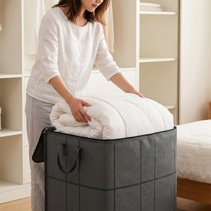 Detail of a grey storage bag with a white comforter being placed inside.