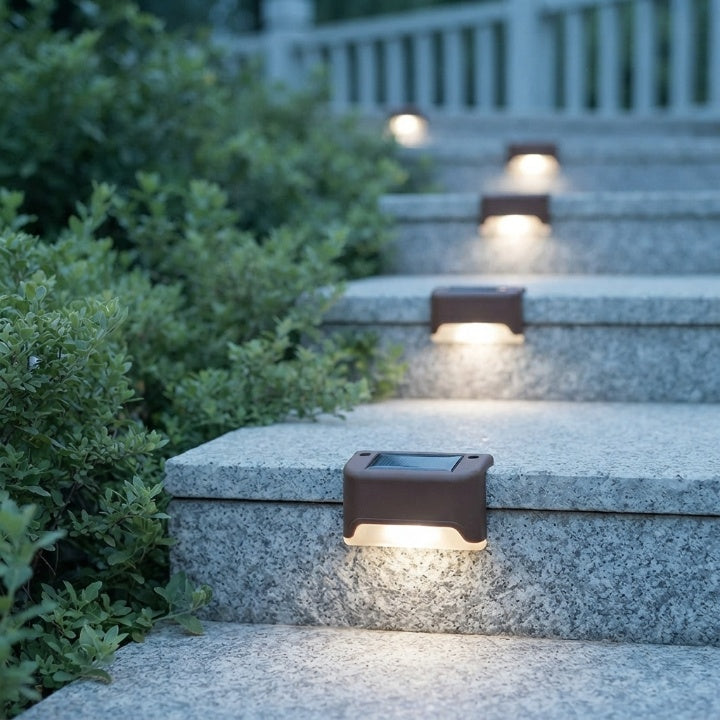 Brown solar step lights casting warm light on granite garden steps lined with green shrubs in the evening.