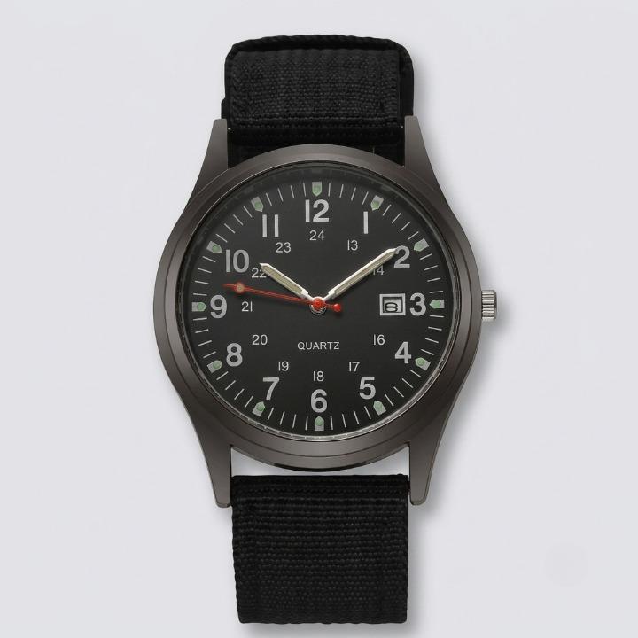 Black military watch with nylon strap, front view on a light background, showing the 24-hour inner ring, date window and red second hand.