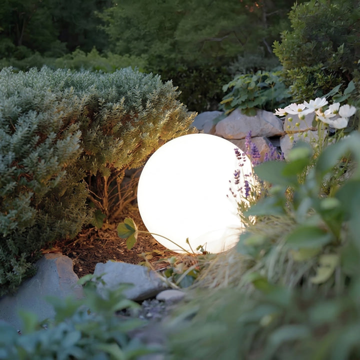 Close view of one white orb light between shrubs, rocks and lavender