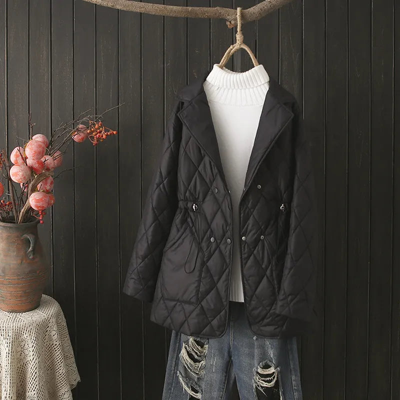 Schwarze gesteppte Damenjacke, elegant, Herbstmode, vor Holzwand drapiert.